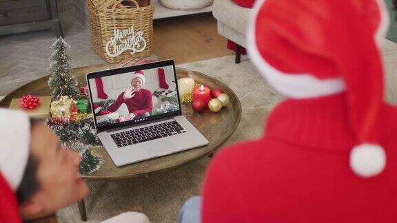 戴着圣诞帽的非洲裔美国家庭使用笔记本电脑与屏幕上的男人进行圣诞视频通话
