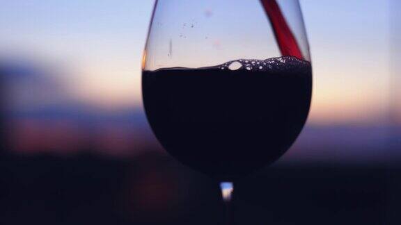 在日落时分将红酒倒入杯中