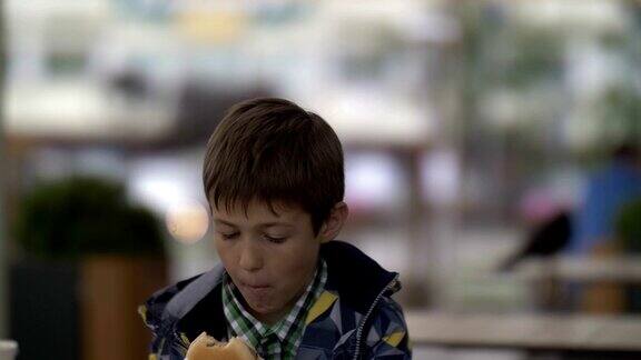 少年坐在城里的咖啡馆里吃汉堡