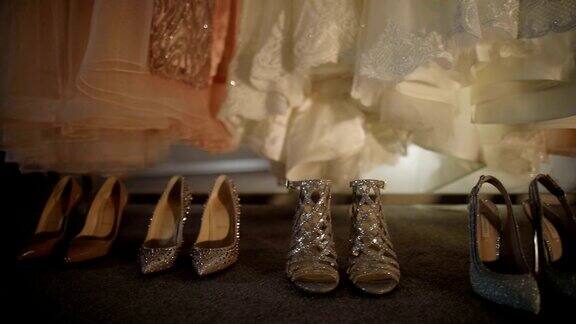 新娘伴娘礼服婚纱和鞋子在仪式前挂在窗前