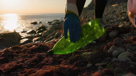 生态保护与地球日一个志愿者走在海滩上捡起一个塑料瓶海岸清洁回收世界环境日与海洋污染