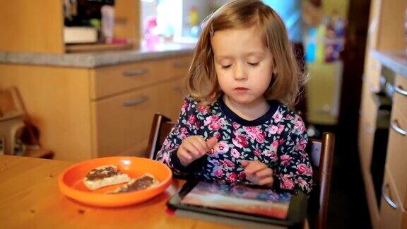 小女孩坐在餐桌前用iPad吃麦片