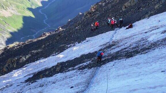 一名戴着红色头盔的登山者沿着冰碛石行走用登山杆沿着带保护绳的绳子移动