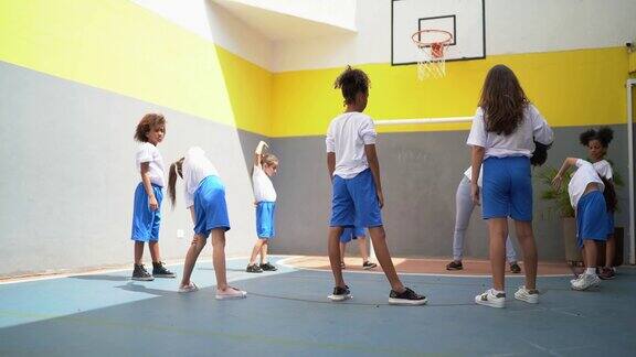 体育活动老师在学校和学生们一起伸展手臂
