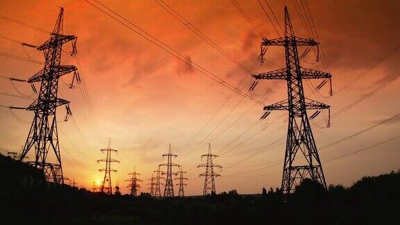 高压电线的支架映衬着红色的夕阳夕阳和电力线塔剪影在史诗般的日落天空