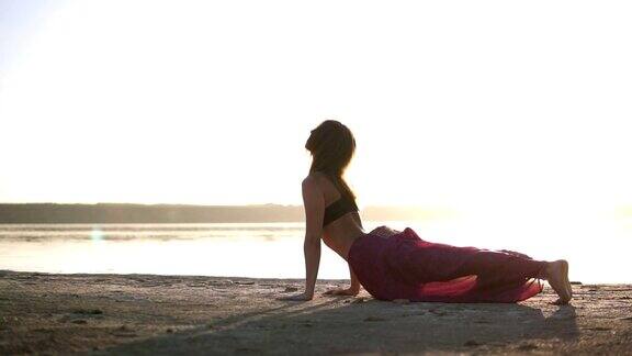 穿着瑜伽服的女人在海边做瑜伽的姿势瑜伽姿势-眼镜蛇冥想体式Bhujangasana