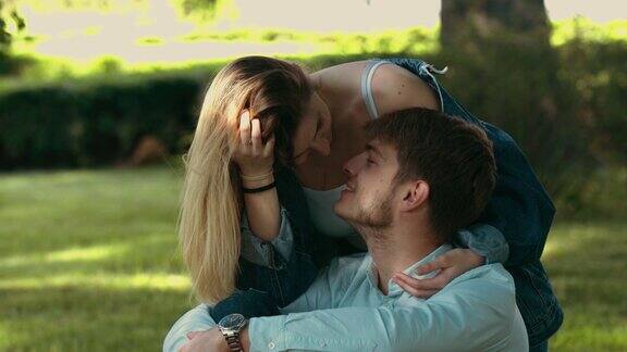 一对年轻情侣在公园的草地上拥抱亲吻