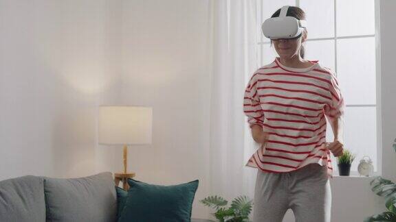 年轻女性戴上VR头戴式耳机在家中客厅体验模拟数字世界跑步游戏动作模拟器游戏手机app