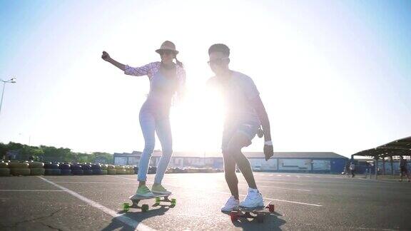 年轻迷人的混合比赛夫妇骑滑板和有乐趣慢动作
