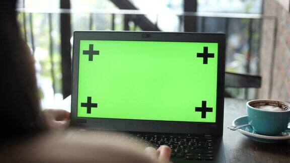 女人看着绿色屏幕的笔记本电脑