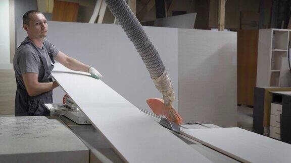 两名木工在家具厂的工业锯床上指导木板切割家具毛坯