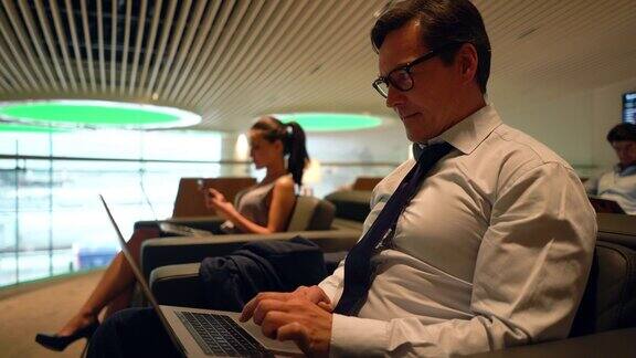 一个成年商人在机场的贵宾休息室里用笔记本电脑工作