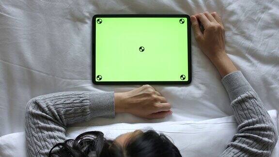 女性在床上使用绿色屏幕的平板电脑高视角水平视角