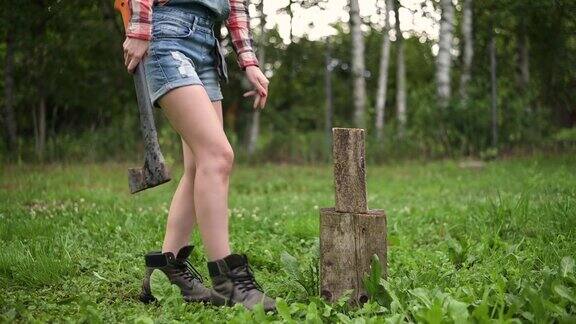 一个年轻的女人正拿着斧头去砍柴她放下了圆木