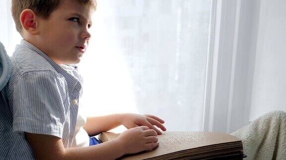 手持盲文书的盲人孩子坐在窗台上读汉字字体