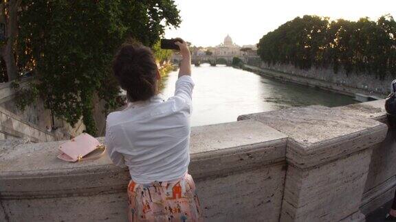 年轻女子在罗马台伯河上的一座桥上拍照圣彼得和梵蒂冈城意大利