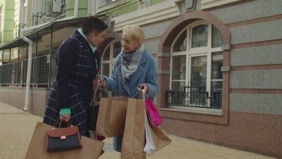 一位上了年纪的朋友在户外向她的伴侣展示用纸包装的商品