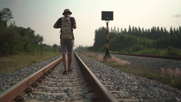 一个男性背包客沿着铁路走
