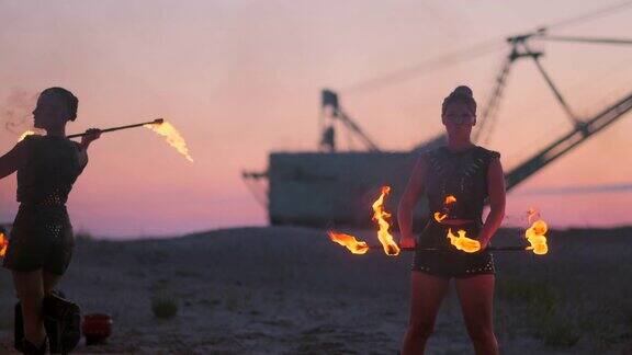 一群男人和女人晚上在沙滩上表演篝火背景是火和塔吊