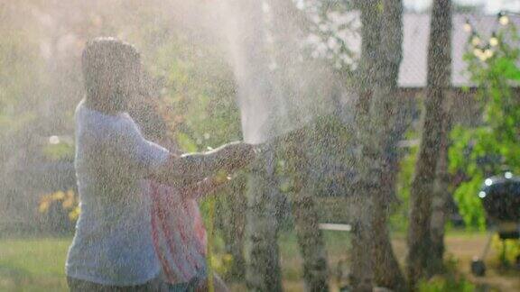 快乐的年轻夫妇在一个炎热的夏天玩水软管洒水器在花园到处喷水弄湿了他们在缓慢的运动