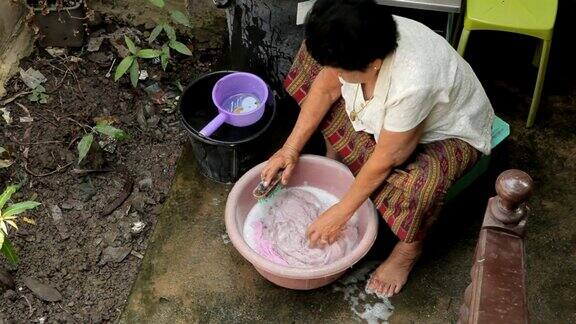 年长的亚洲妇女手洗衣服