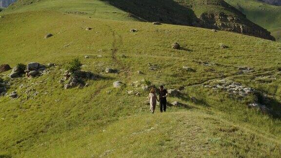 俄罗斯高加索地区一对年轻夫妇手牵手从山上下来