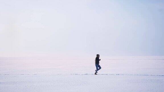 宽阔的镜头男性侧影在雪地上快乐地奔跑和跳跃