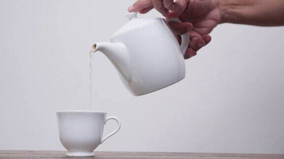 老女人把茶倒进白色背景的杯子里