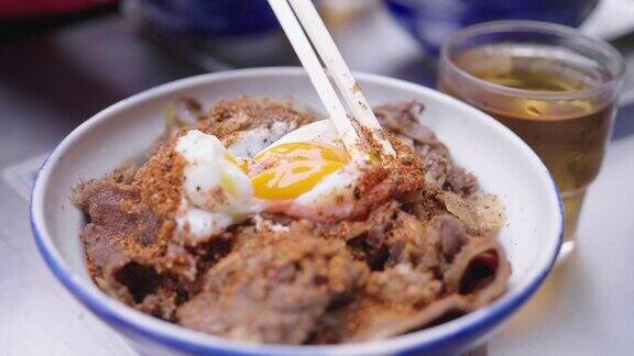用筷子搅开温泉蛋和牛肉拌日式米饭