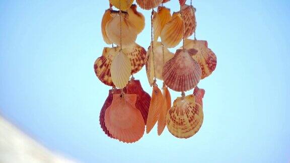 在热带海滩的夏日微风中蓝色天空衬托下的贝壳装饰(风铃)的特写