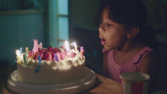 快乐的小女孩吹灭生日蛋糕上的蜡烛