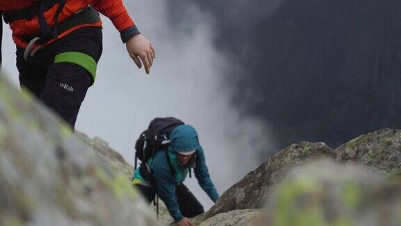 两个徒步旅行者在多云多雾的天气里爬上一座岩石山