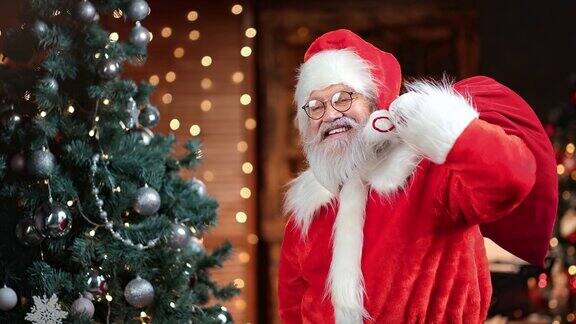 滑稽的男圣诞老人背着礼物袋在圣诞树上挥手红色摄像机中拍摄