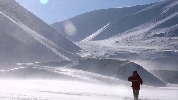 一个孤独的旅行者正穿过暴风雪背景是雪山