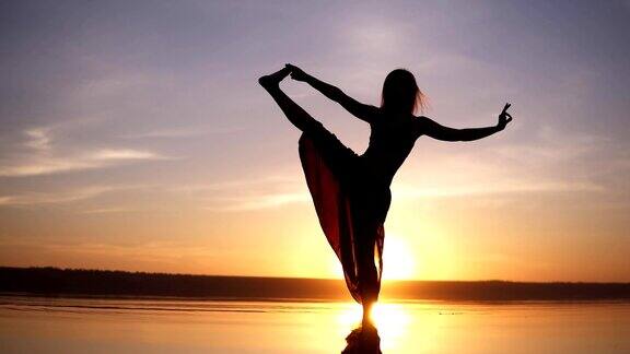 女子练习瑜伽姿势在美丽的日落海岸