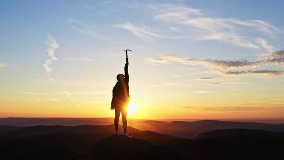 一名女登山者站在山顶享受日落时分的慢镜头