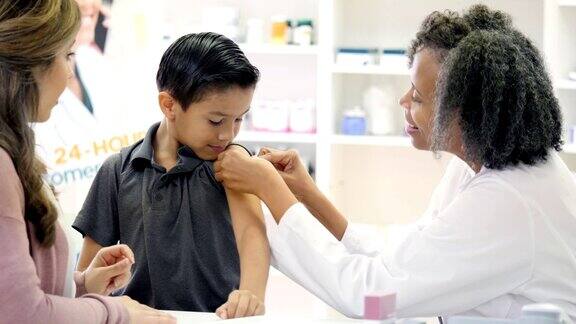 接受疫苗后女药剂师在男孩的手臂上贴绷带