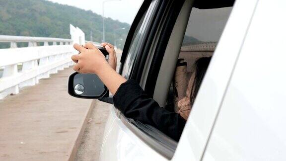 亚洲小女孩在车上拍照旅游摄影概念