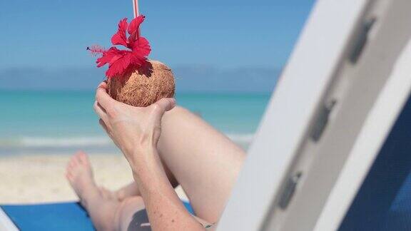 古巴在沙滩上喝着饮料坐在椅子上放松的女人