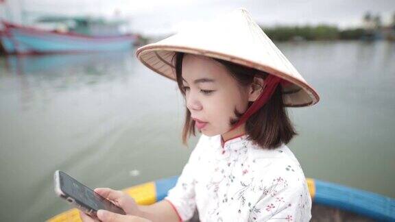 女游客穿着澳雅爱越南传统服装在游船上拍照