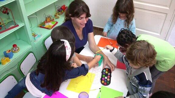 幼儿园的孩子在教室里和老师一起画画