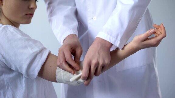 医生包扎受伤病人的手在外伤诊所进行扭伤的急救
