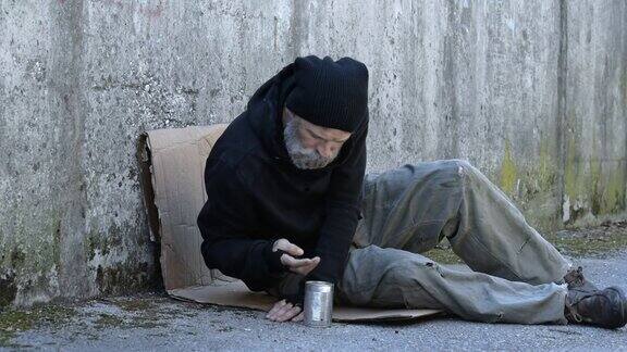 一个无家可归的人坐在地上乞讨