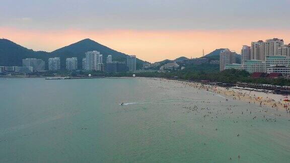 日落天空三亚著名的大东海拥挤的海滩航拍全景4k海南中国