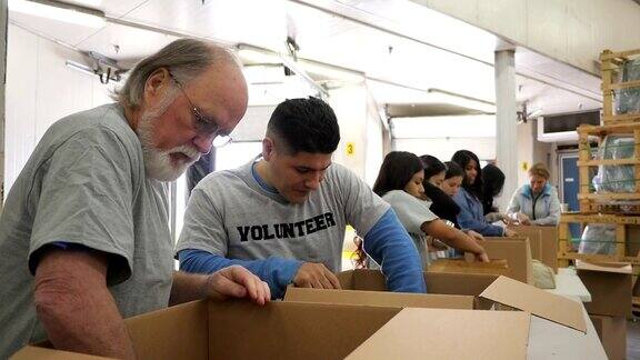 高级男子整理捐赠箱与不同团体的食品银行志愿者