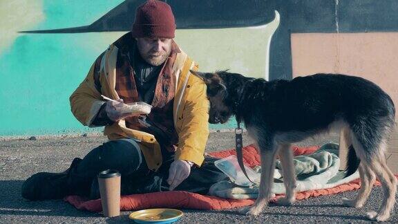 一个无家可归的人和他的狗在街上吃东西