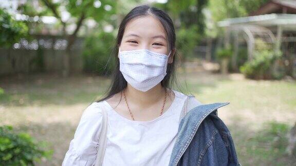 在covid-19冠状病毒情况下亚洲少女戴着面具微笑的肖像
