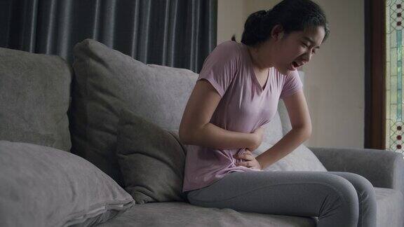 亚洲少女有盆腔疼痛胃痛而坐在家里的沙发上