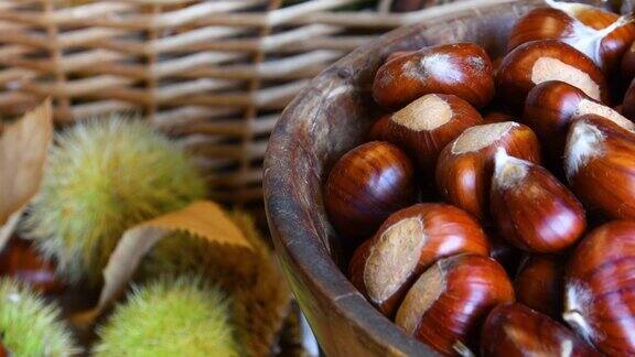 这是一个木碗里新鲜采摘的栗子的特写背景是模糊的绿色刺猬十月栗子收获的季节典型的秋季新鲜水果
