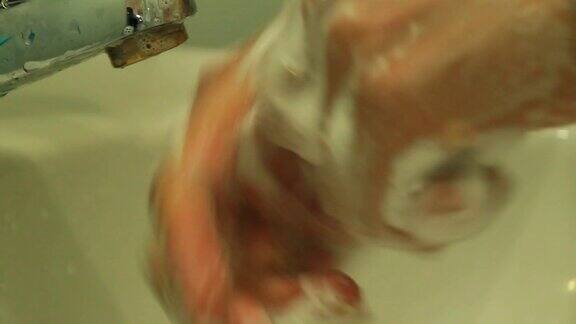 小女孩在水龙头下用肥皂洗手